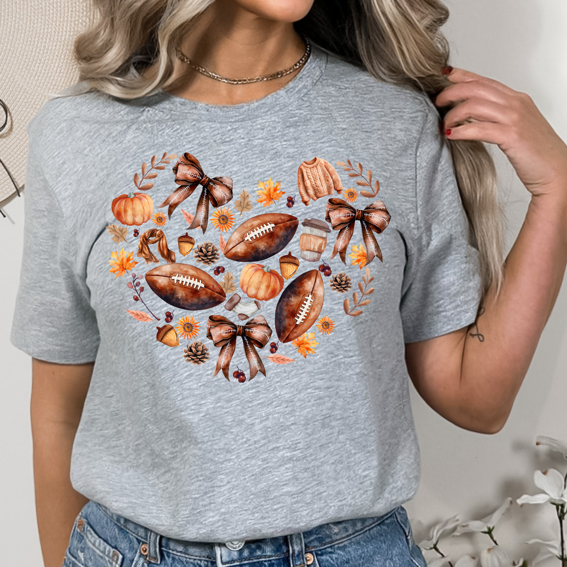 Fall Football & Pumpkin Bow Heart Unisex Shirt in pastel pink. The shirt features a beautiful autumn design with footballs, pumpkins, acorns, bows, and leaves arranged in a heart shape. Perfect cozy tee for fall, football season, and game day events.