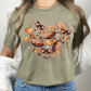 Fall Football & Pumpkin Bow Heart Unisex Shirt in pastel pink. The shirt features a beautiful autumn design with footballs, pumpkins, acorns, bows, and leaves arranged in a heart shape. Perfect cozy tee for fall, football season, and game day events.