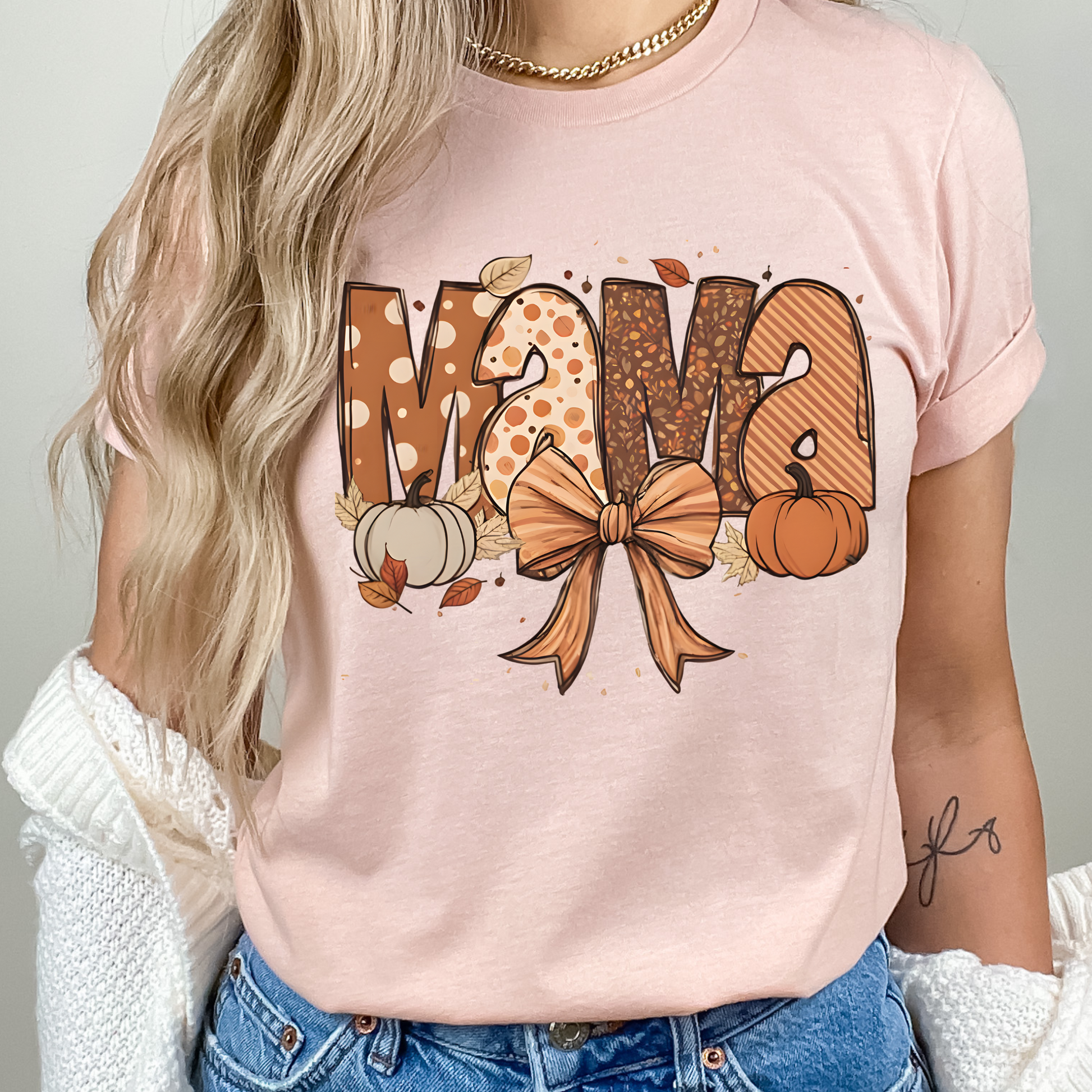 Fall Mama Shirt in soft pink featuring cute pumpkins, fall leaves, and a stylish bow design. Perfect graphic tee for autumn-loving moms.