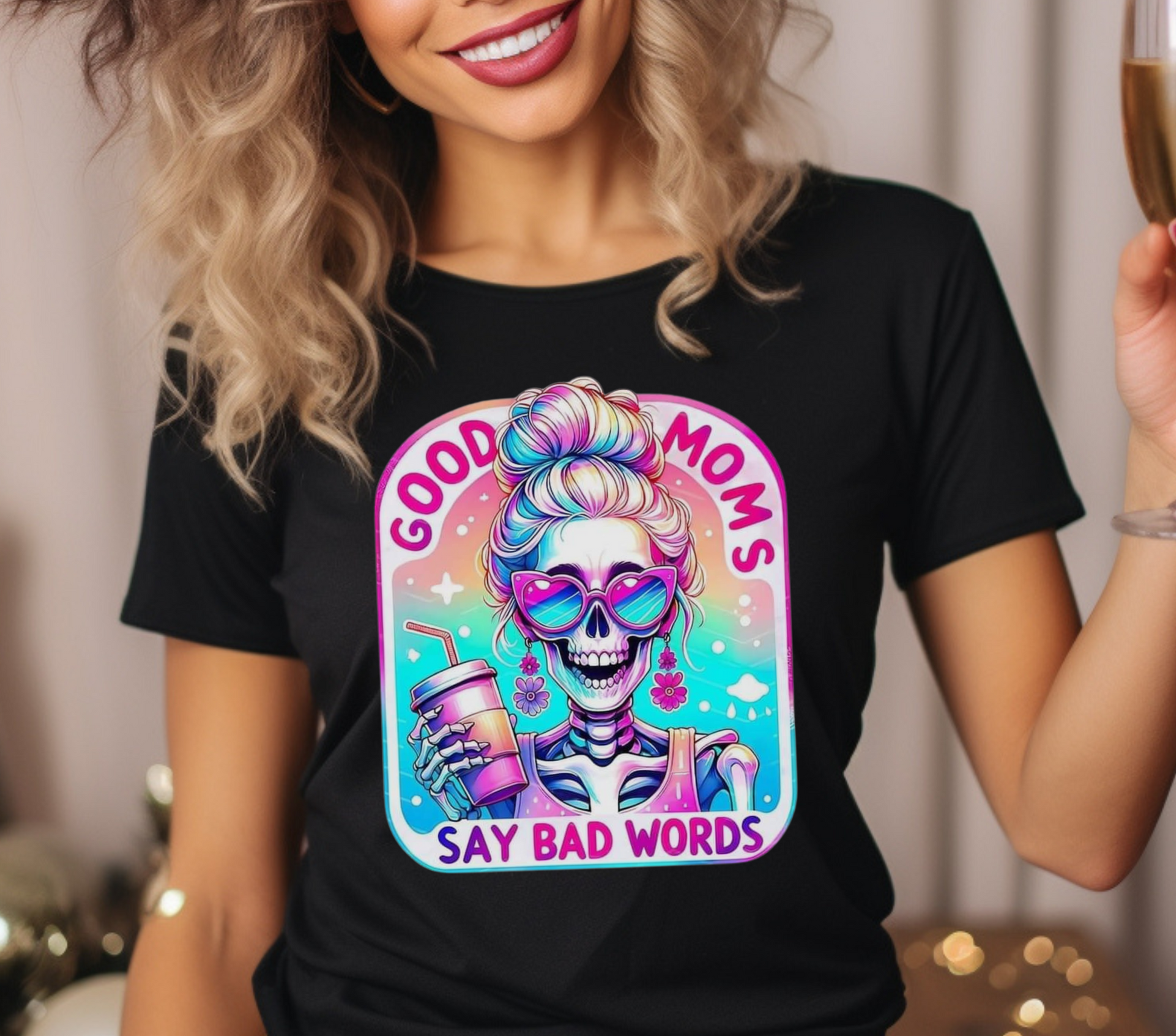 Good Moms Say Bad Words Messy Bun Colorful Skeleton Iced Coffee Shirt. Features a vibrant, retro-style graphic of a skeleton with a messy bun holding an iced coffee, with the text 'Good Moms Say Bad Words.' Soft cotton material in a unisex fit, available in multiple colors. Ideal for casual wear and making a fun, playful statement. Machine washable for easy care.