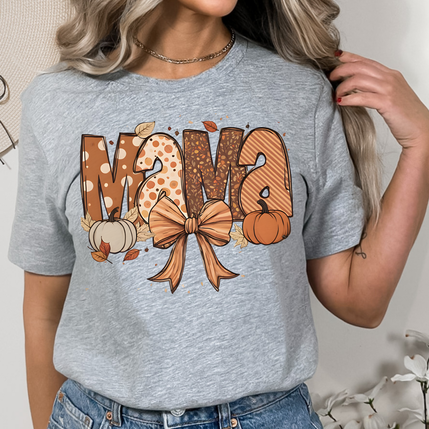 Fall Mama Shirt in soft pink featuring cute pumpkins, fall leaves, and a stylish bow design. Perfect graphic tee for autumn-loving moms.