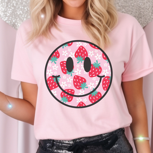 Pink background shirt featuring a strawberry and daisy smiley face design for a playful, cheerful look. Unisex fit, perfect for casual days