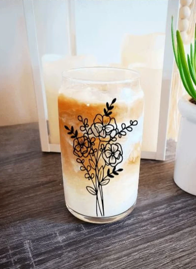 Vaso de café helado con lata de cerveza y flores silvestres